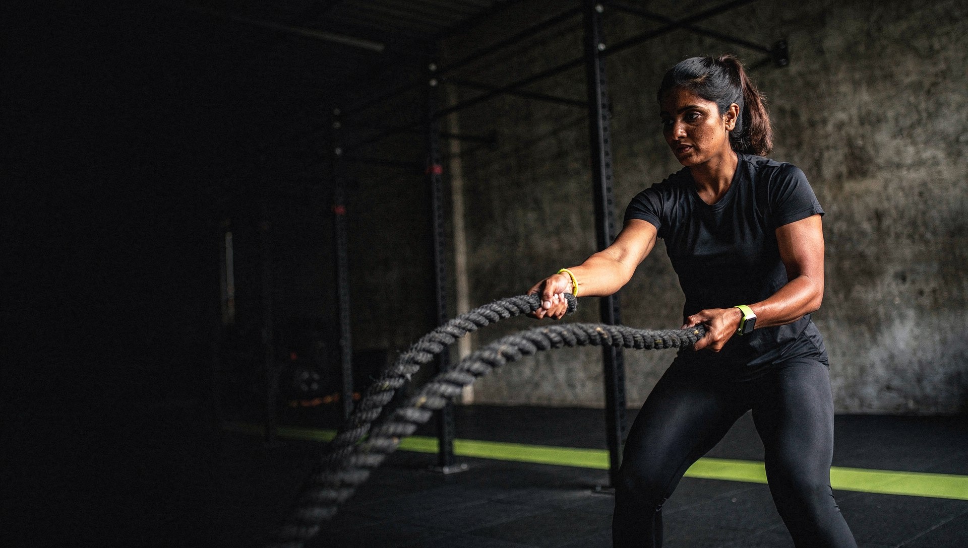 Athlete training with battle ropes in a sunlit industrial gym